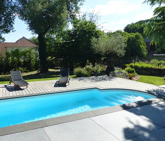 Piscine margelles grises et plage en bois