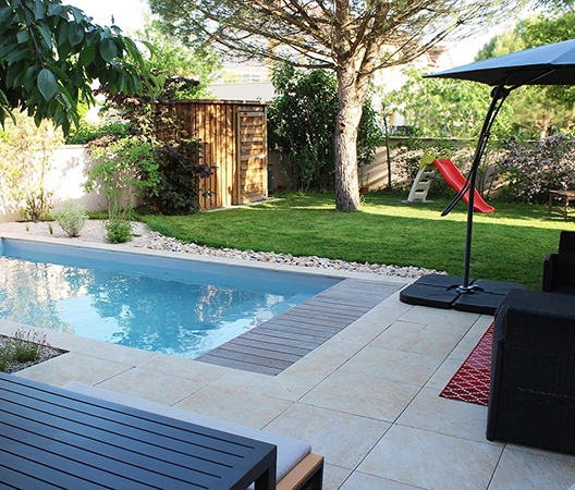 Piscine maçonnée plage en grès cérame et aménagement global du jardin